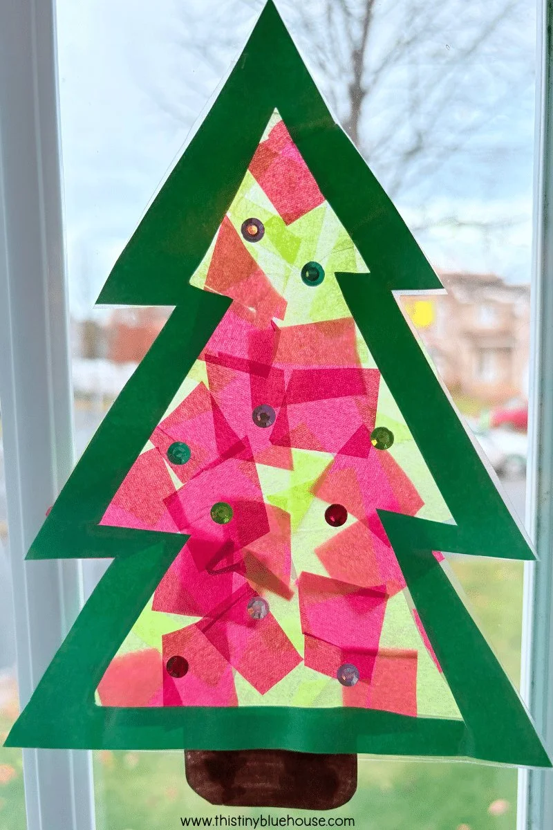 Colorful Christmas Tree sun catcher craft displayed in sunlight.