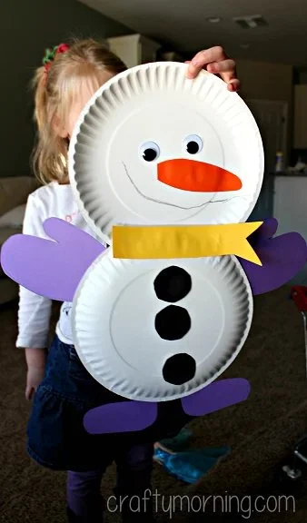 Cute paper plate snowman craft for kids featuring winter decorations.