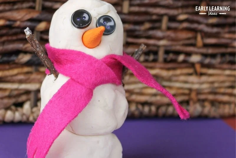 Child making a playdough snowman in a winter-themed activity